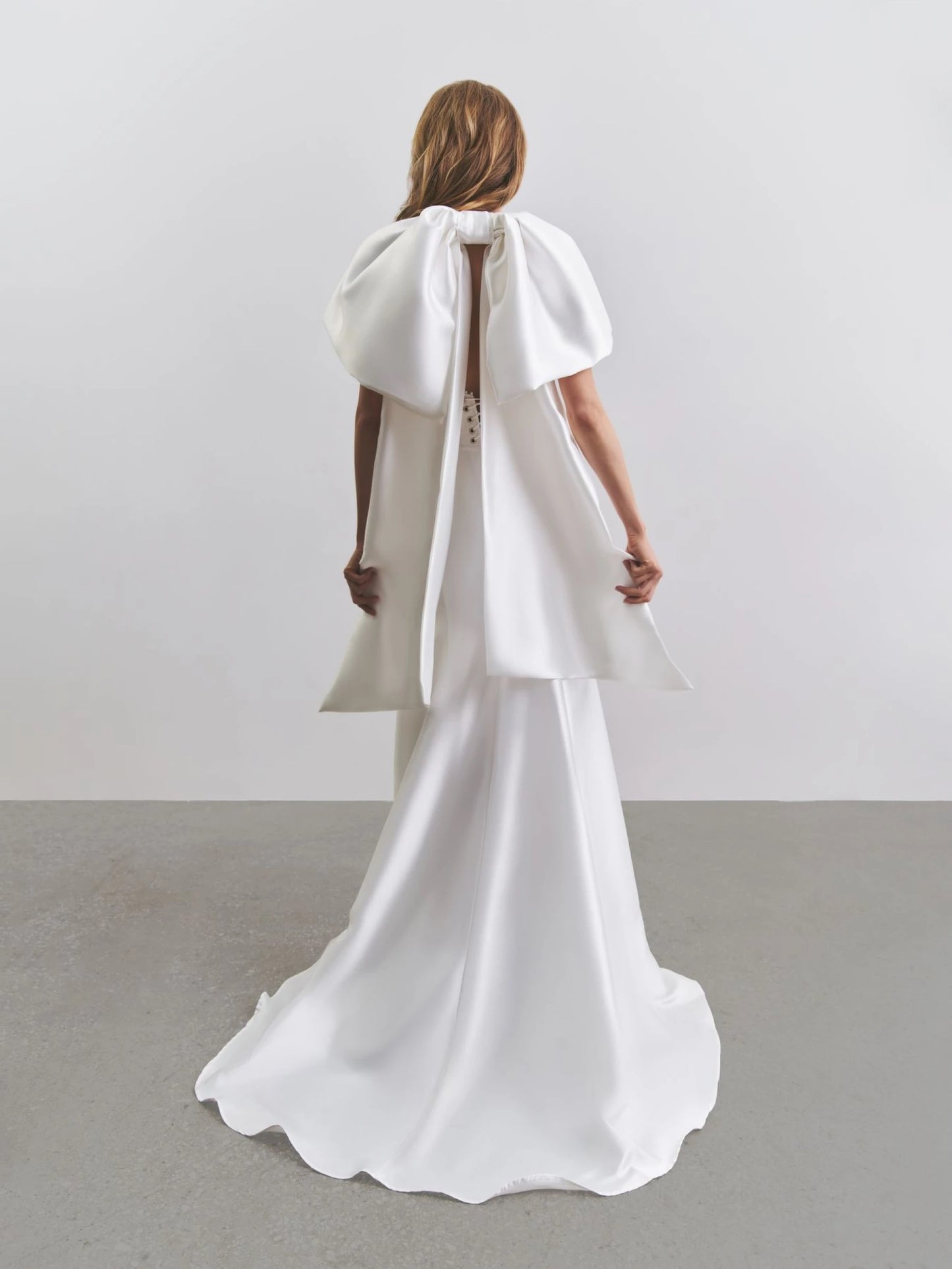Back view of Goccia Liretta dress showing dramatic bow and fishtail skirt detail