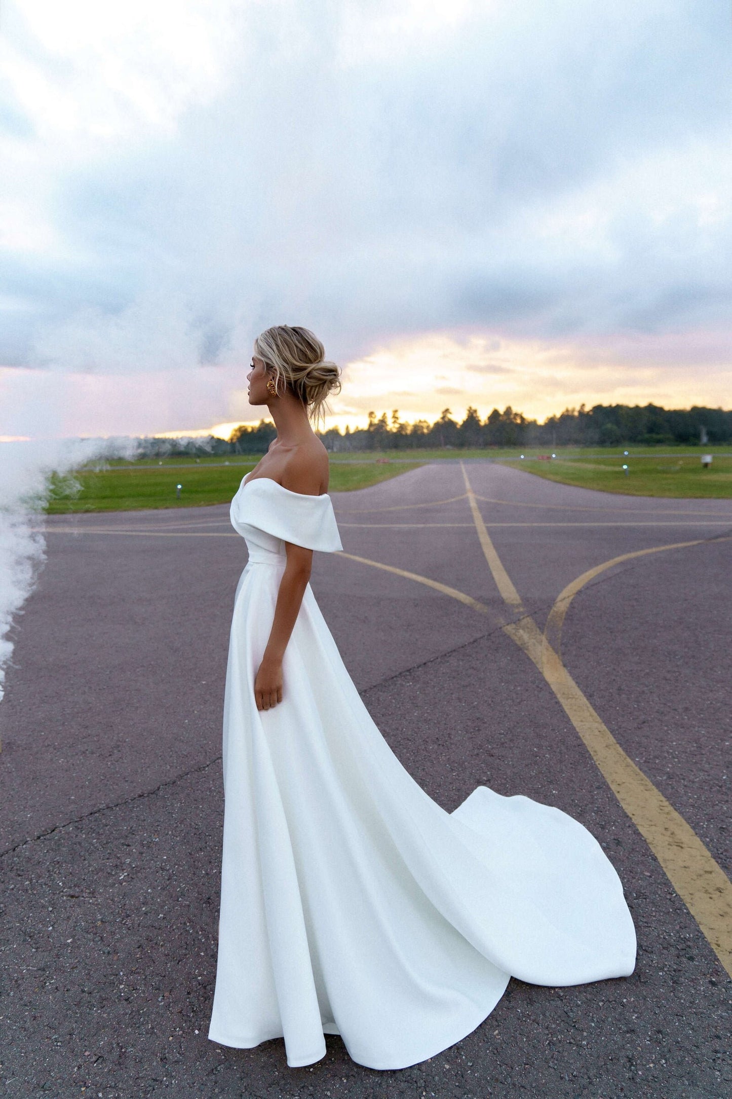 Side view of Greta bridal gown with dramatic train and fitted crepe skirt at sunset