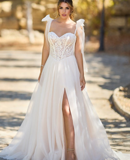 Eenika by Très Chic A-line corset wedding dress with lace bodice, sweetheart neckline, tulle bow straps, glitter tulle skirt and front slit