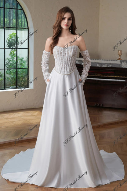 Front view of Eugénie off-shoulder lace corset wedding dress with long lace sleeves and satin A-line skirt with pockets