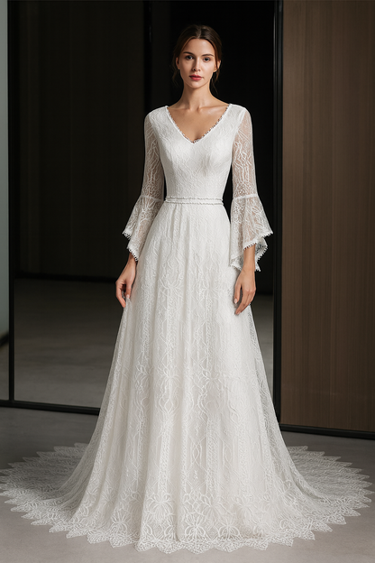 Model wearing a white lace wedding dress with long sleeves in a dark room.