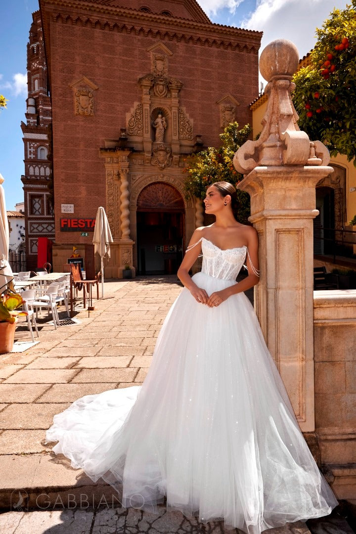 Bride wearing the Isolda gown in front of historic building, showing lace bodice and full tulle skirt