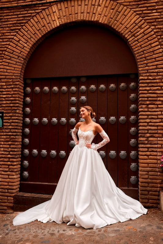 Bride in Secret Sposa Parish gown standing in front of ornate door, showing lace corset and satin skirt