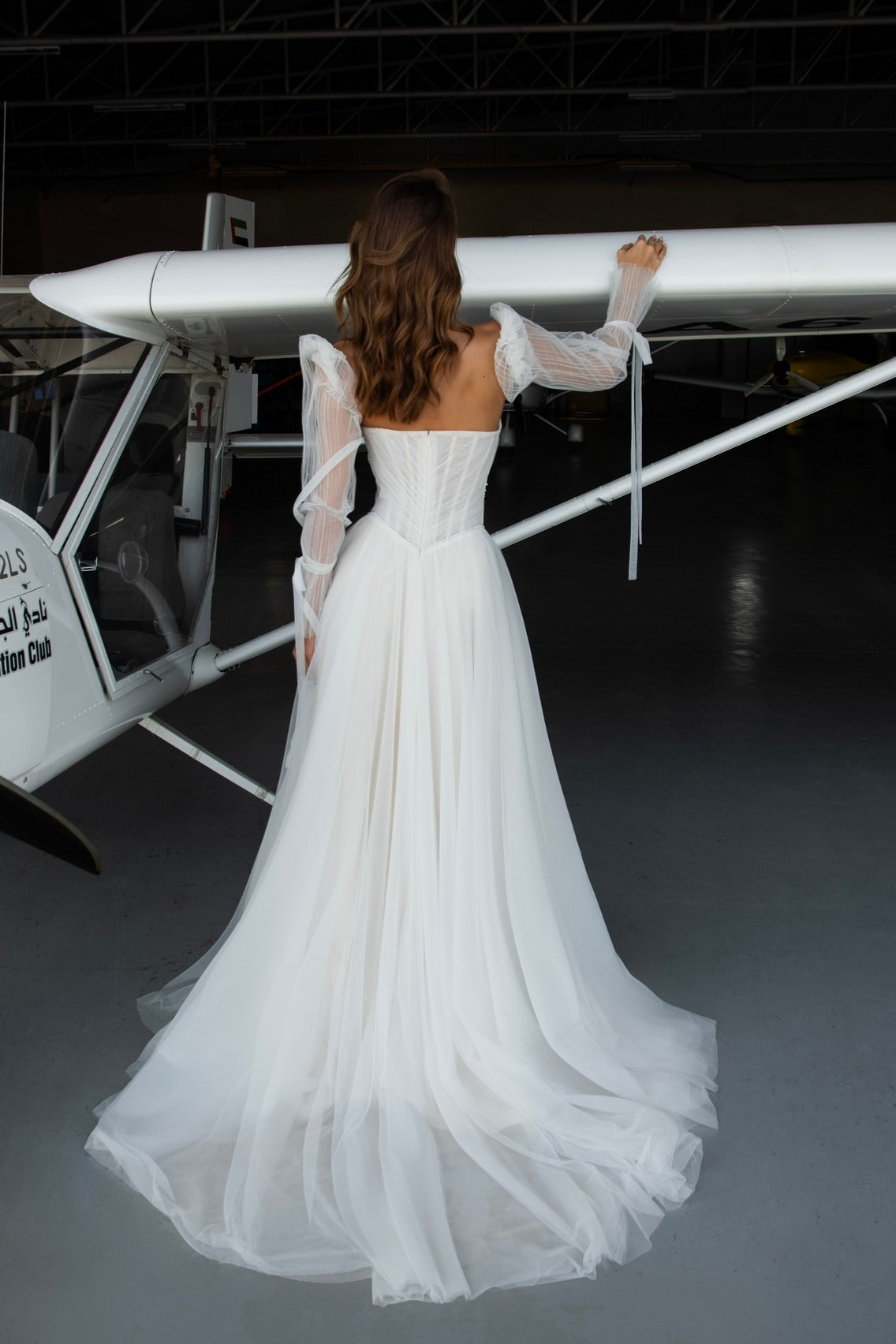 Kris wedding gown – light tulle A-line skirt with flowing train and optional sheer sleeves; clean back with zipper.