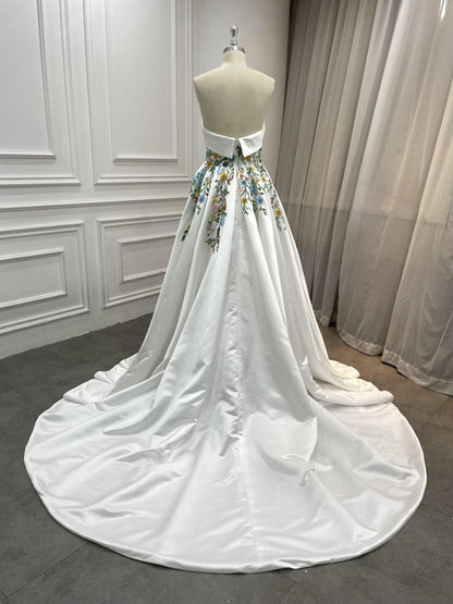 Back of Aster wedding gown showing clean strapless line, floral embroidery at waist, and chapel-length train
