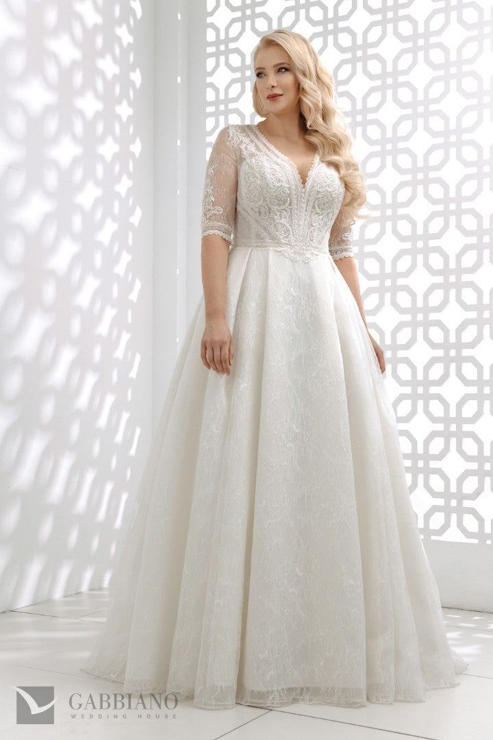Bride wearing Chester wedding dress by Gabbiano — lace A‑line wedding gown with illusion sleeves and deep V-neck